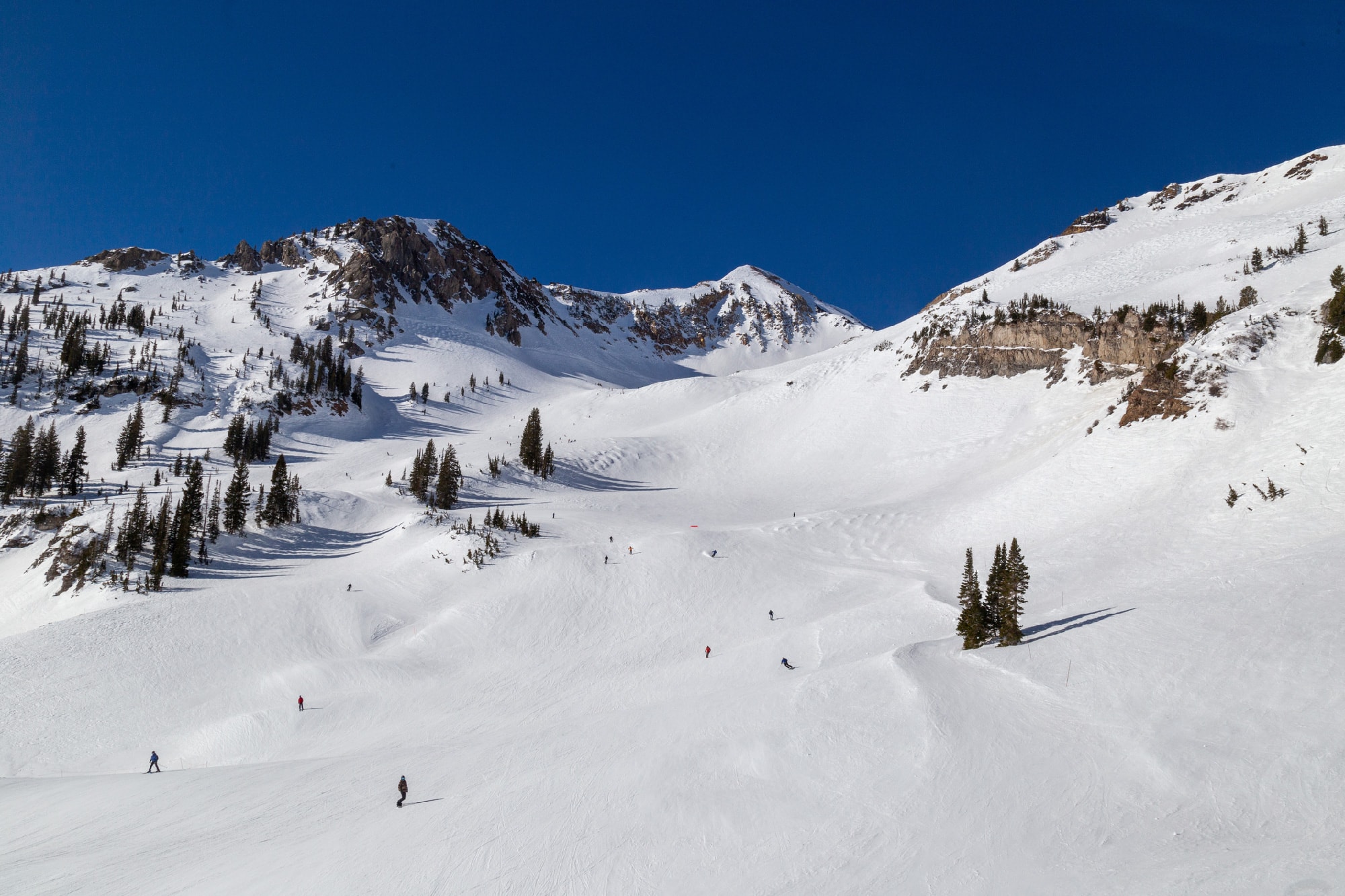 People snowboarding down snowy mountain near Salt Lake City